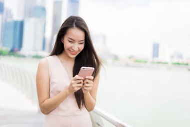 Asyalı kadın konuşmak veya metin için akıllı telefon veya cep telefonu kullanarak