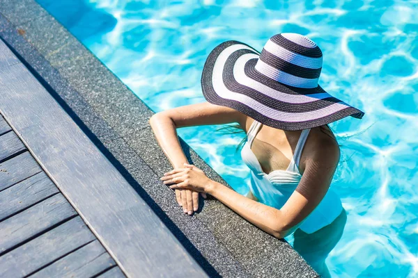 Bonita jovem mulher asiática com chapéu na piscina para viagens — Fotografia de Stock