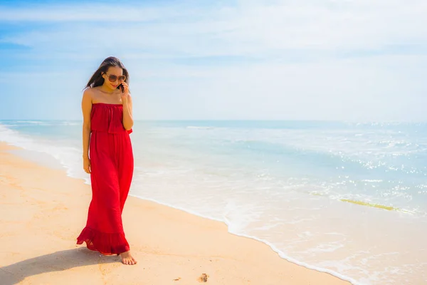 レジャー休暇の概念のためのビーチや海の散歩と携帯電話や携帯電話を使用して美しい若いアジアの女性を肖像 — ストック写真