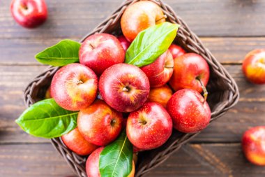 Bir sürü tablo üzerinde kahverengi sepet içinde kırmızı elma meyve