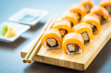 Somon Balık et suşi roll maki wasabi ve soya sosu - Japon yemekleri tarzı ahşap plaka üzerinde