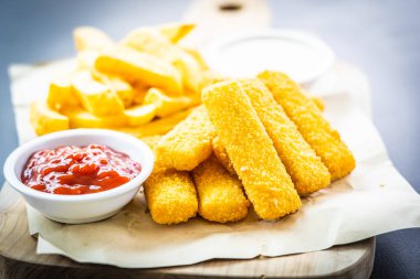 Balık parmak ve patates kızartması veya ahşap kesme tahtası - sağlıksız yiyecek stil üzerinde domates ketçap ve mayonez soslu cips