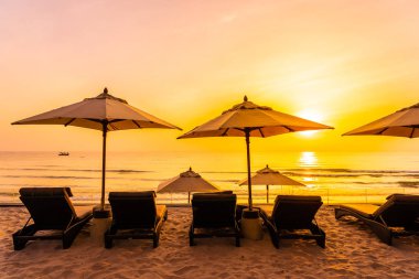 Şemsiye ve şezlong üzerinde güzel plaj ve gündoğumu zaman seyahat ve tatil için deniz