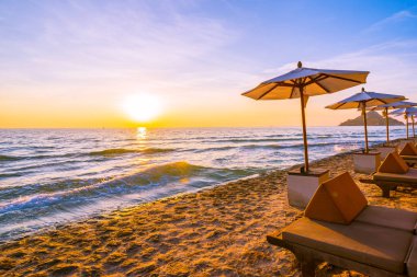 Şemsiye ve plaj ve deniz tatil tatil ve seyahat için gündoğumu veya günbatımı zaman güzel peyzaj etrafında yastık ile sandalye