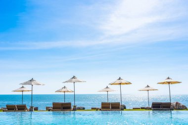Deniz okyanus üzerinde sky şemsiye ve lüks Açık Yüzme havuzunda hotel resort tatil seyahat ve tatil için çevresinde sandalye ile güzel manzara
