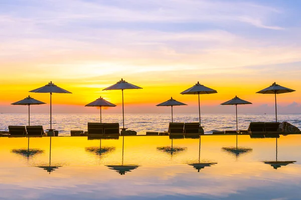 日落或日出时 可在度假酒店的游泳池周围放置雨伞和椅子 供游玩及度假之用 — 图库照片