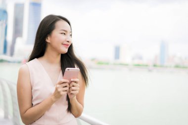 Güzel Asyalı kadın konuşmak veya metin için akıllı telefon veya cep telefonu kullanarak