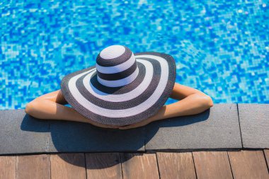 Güzel genç Asyalı kadın mutlu gülümseme ve resort otel eğlence seyahat ve tatil için yüzme havuzunda rahatlayın