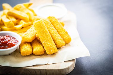 Balık parmak ve patates kızartması veya ahşap kesme tahtası - sağlıksız yiyecek stil üzerinde domates ketçap ve mayonez soslu cips