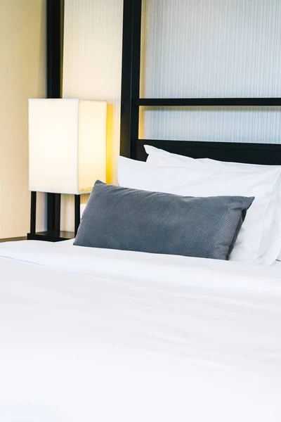 Vacker lyxig bekväm kudde på sängen med ljus lampa — Stockfoto