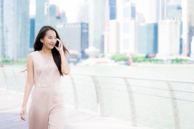 Asyalı kadın konuşmak veya metin için akıllı telefon veya cep telefonu kullanarak