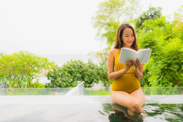 Retrato hermosa joven asiática mujer leyendo libro en natación po — Foto de Stock