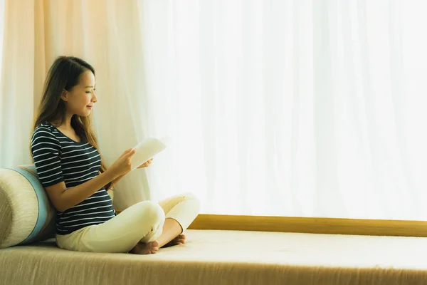 Retrato hermosa joven asiática mujer leyendo libro en en sofá en —  Fotos de Stock