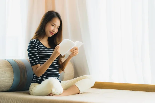 Retrato hermosa joven asiática mujer leyendo libro en en sofá en —  Fotos de Stock