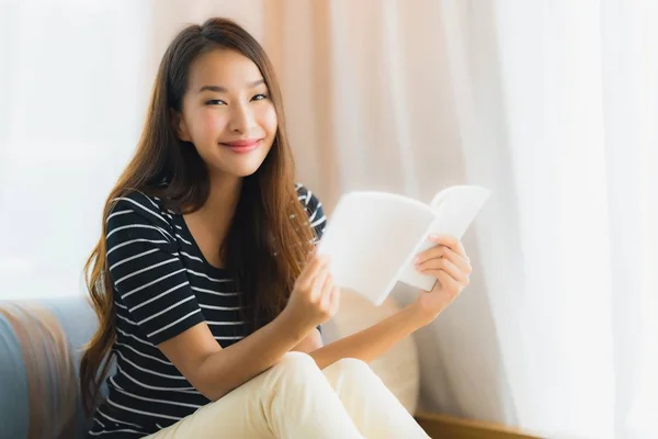 Retrato hermosa joven asiática mujer leyendo libro en en sofá en —  Fotos de Stock