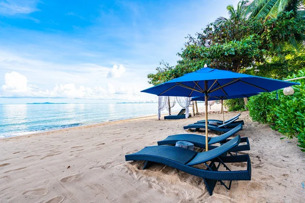 Hermosa sombrilla y silla de cama vacía en la playa tropical y —  Fotos de Stock