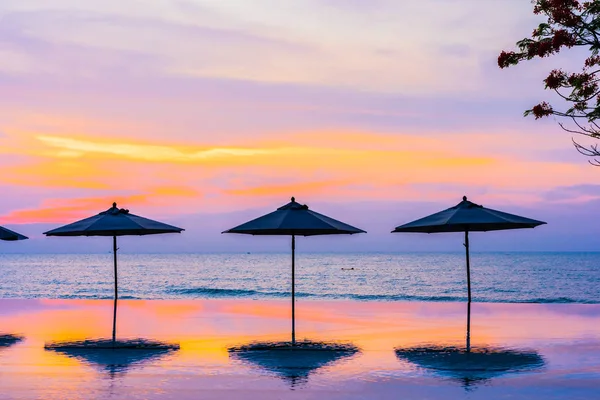 Зонтик и стул вокруг бассейна на пляже у моря — стоковое фото