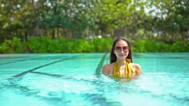 Güzel Asyalı bir kadının oteldeki havuzda dinlenirken çekilmiş görüntüleri.