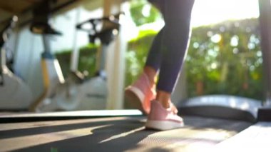 Spor yaparken koşu bandında yürüyen bir kadının görüntüsü.