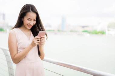 Asyalı kadın konuşmak veya metin için akıllı telefon veya cep telefonu kullanarak