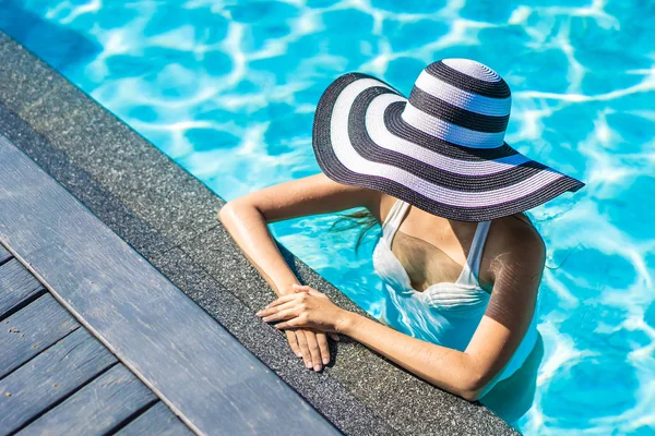 Bonita jovem mulher asiática com chapéu na piscina para viagens — Fotografia de Stock