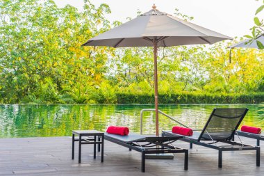 Otel tesisinde yüzme havuzu çevresinde şemsiye ve sandalye