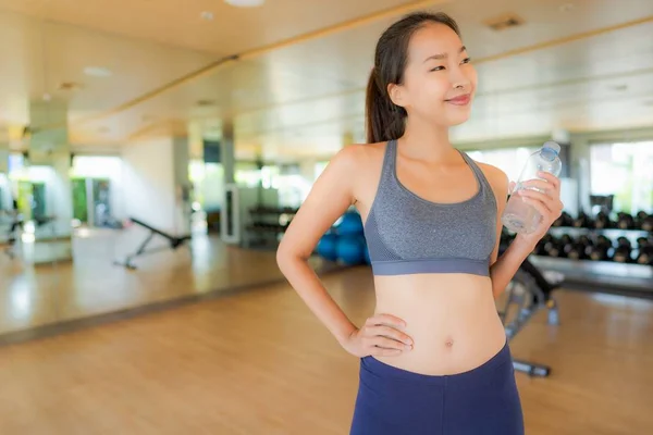 Ritratto bella giovane donna asiatica con bottiglia d'acqua in palestra — Foto Stock