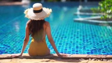 Güzel Asyalı bir kadının oteldeki havuzda dinlenirken çekilmiş görüntüleri.