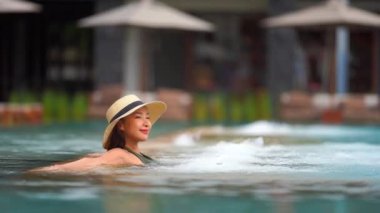 Güzel Asyalı bir kadının oteldeki havuzda dinlenirken çekilmiş görüntüleri.