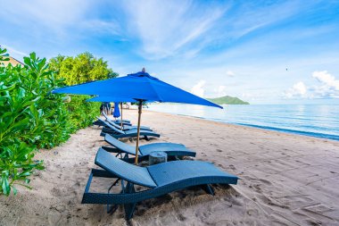 Tropikal plajda güzel şemsiye ve boş yatak sandalyesi ve