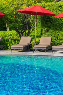 Sıcak açık yüzme havuzu etrafında güzel şemsiye ve sandalye