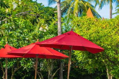 Sıcak açık yüzme havuzu etrafında güzel şemsiye ve sandalye