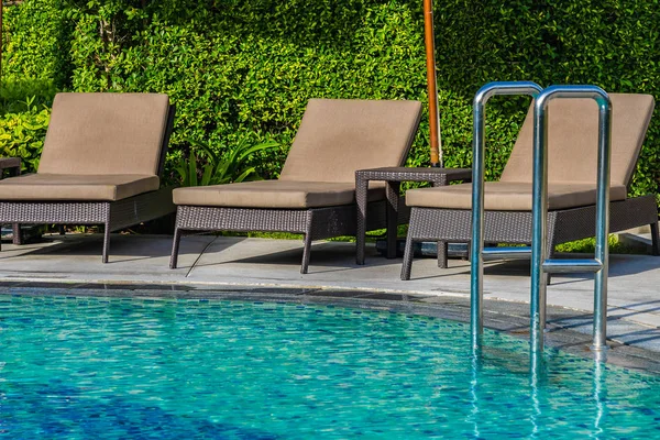 Hermoso paraguas y silla alrededor de la piscina al aire libre en caliente —  Fotos de Stock