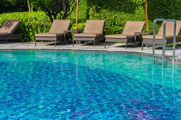 Hermoso paraguas y silla alrededor de la piscina al aire libre en caliente —  Fotos de Stock