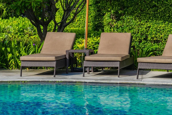 Hermoso paraguas y silla alrededor de la piscina al aire libre en caliente —  Fotos de Stock