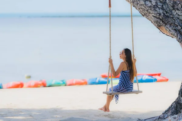 Портрет молодой азиатской женщины, сидящей на качелях и море вокруг — стоковое фото