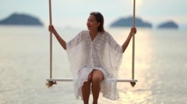 yaz tatili sırasında deniz kıyısında salıncak oturan güzel asya kadın görüntüleri