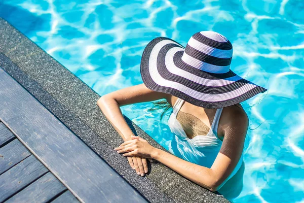 Seyahat için yüzme havuzunda şapkalı güzel genç Asyalı kadın — Stok fotoğraf