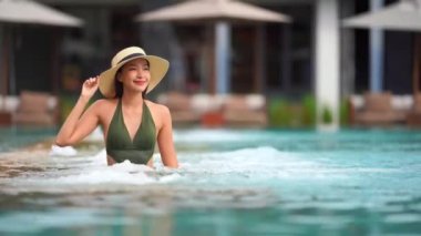 Güzel Asyalı bir kadının oteldeki havuzda dinlenirken çekilmiş görüntüleri.