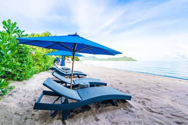 Tropikal plajda güzel şemsiye ve boş yatak sandalyesi ve