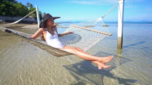 夏休み中に海岸のハンモックに横たわっている美しいアジアの女性の映像 — ストック動画