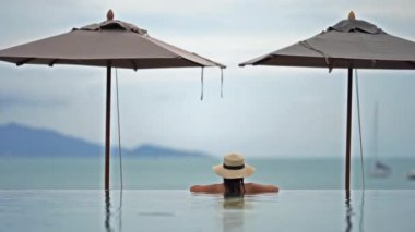 Güzel Asyalı bir kadının oteldeki havuzda dinlenirken çekilmiş görüntüleri.