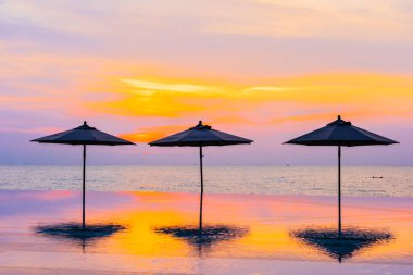 Şemsiye ve sandalye yüzme havuzu yakınında deniz okyanus plaj