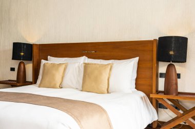 Yatak üzerinde güzel konforlu lüks beyaz yastık ve battaniye Dec