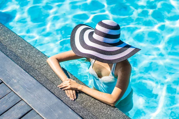 Bonita jovem mulher asiática com chapéu na piscina para viagens — Fotografia de Stock