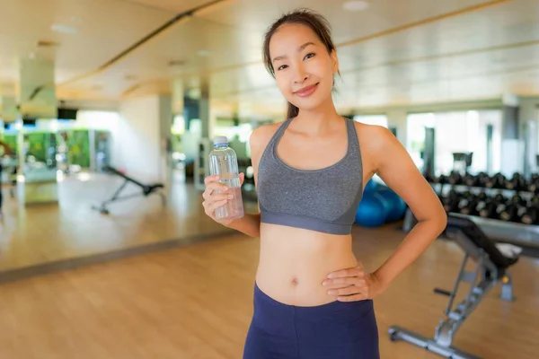 Ritratto bella giovane donna asiatica con bottiglia d'acqua in palestra — Foto Stock