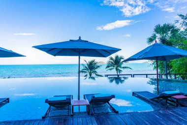 Şemsiye ve güzel lüks açık yüzme havuzu etrafında sandalye