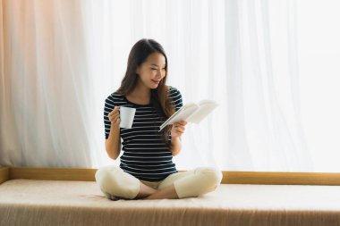 Portre güzel genç Asya kadın okuma kitap ve hold coffe