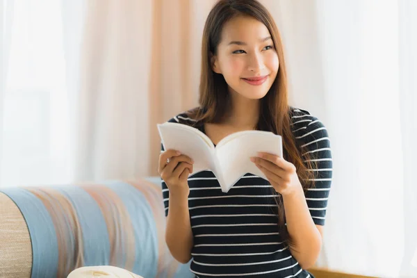 Retrato hermosa joven asiática mujer leyendo libro en en sofá en —  Fotos de Stock