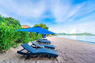 Tropikal plajda güzel şemsiye ve boş yatak sandalyesi ve